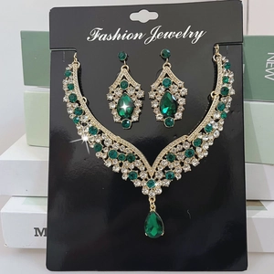 Detail of vintage gold alloy jewelry set featuring teardrop green gemstones and rhinestones