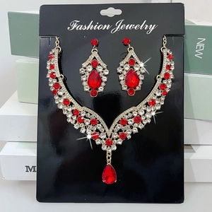 Detail view of gold V-shaped necklace and red teardrop earrings on jewelry card