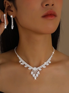 Gros plan sur une parure de mariée avec collier en V argenté et boucles d'oreilles