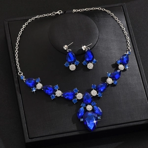 Dettaglio di collana e orecchini con zaffiro blu a goccia su confezione regalo nera