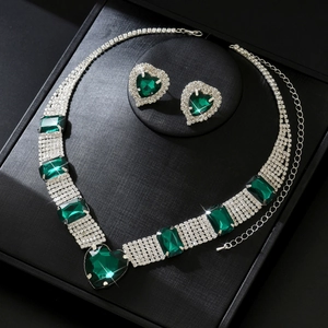 Detailed close-up of emerald green heart necklace and stud earrings in black jewelry box