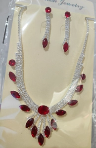 Détail macro du collier et des boucles d'oreilles argentés avec gemmes rouges