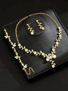 Detailed close-up of golden rhinestone bridal necklace set on a textured black display