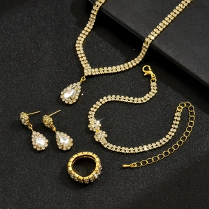 Flat lay of gold bridal jewelry set featuring water drop rhinestones on black background