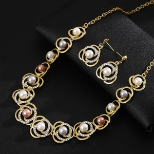 Elegant pearl necklace and earrings set with gold rings and rhinestones on black background
