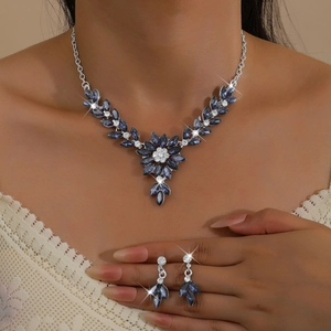 Detail of floral bridal jewelry set with navy blue stones on lace dress