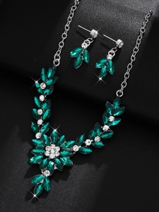 Macro shot of silver floral jewelry set with emerald marquise and round white diamonds