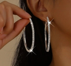 Close-up of a large silver hoop earring with sparkling rhinestones on a female model