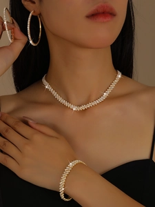 Sparkling gold-toned jewelry set with necklace, bracelet, and hoop earrings on model
