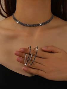 Detailed view of silver choker necklace and large hoop earrings with black zircon stones
