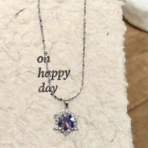 Detail van sneeuwvlok hanger met blauw kristal en witte zirkonia op zilveren ketting