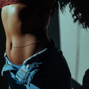 Gros plan artistique d'une délicate chaîne de taille perlée dorée sur le corps de la femme