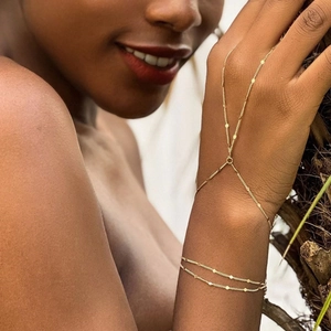 Detailansicht eines goldfarbenen Fingerkettchen-Armbands mit kleinen Pailletten am Hand
