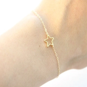 Close-up of minimalist gold-colored bracelet with hollow star pendant on wrist