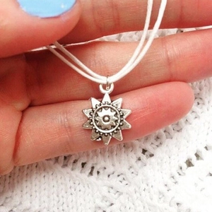 Dettaglio del ciondolo girasole in argento vintage con cordoncino di velluto bianco su pizzo
