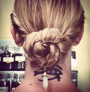 Detail of bohemian gold moon hair pin with a white hexagonal crystal pendant on hair