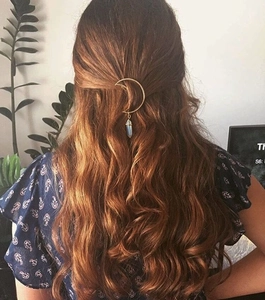 Detail of a gold moon hair clip with crystal pendant styled in a half-up hairstyle