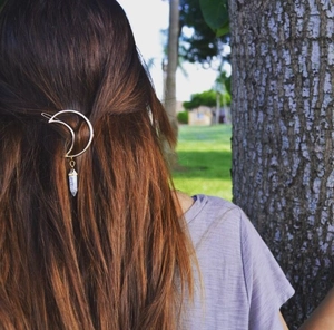 Golden moon hair clip with hexagonal crystal pendant styled on dark brown wavy hair