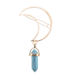 Detail of moon-shaped golden hair clip with a blue hexagonal stone pendant