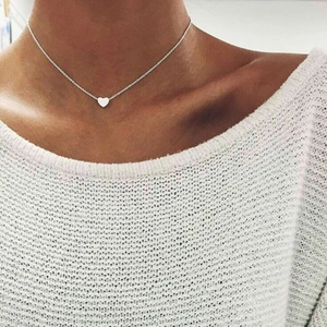 Close-up of minimalist silver heart pendant necklace worn on a woman's collarbone