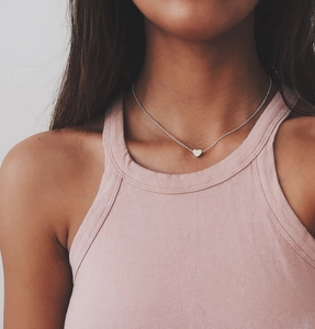Close-up of a minimalist silver heart pendant necklace worn on the collarbone