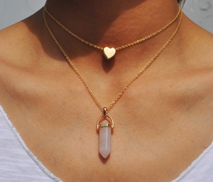 Close-up of double layer gold necklace with pink hexagonal crystal and heart pendant