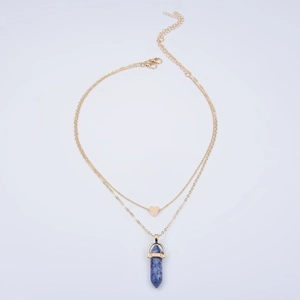 Detail of layered gold necklace with heart pendant and blue hexagonal crystal column