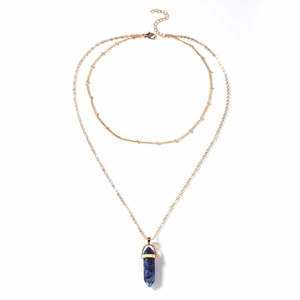 Detailed macro of a double-layered gold chain with a blue hexagonal crystal pendant