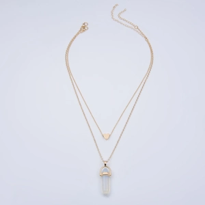 Detail of layered gold necklace featuring a heart pendant and hexagonal stone column