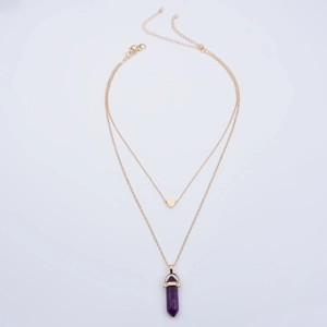 Detail of double-layer gold necklace featuring a heart pendant and purple hexagonal crystal