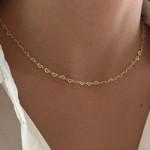 Detailed close-up of a hollow heart-shaped link bracelet in polished golden metal
