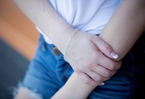 Close-up of minimalist silver heart-shaped chain bracelet worn on a woman's wrist