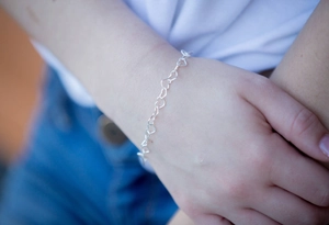 Detailed view of silver minimalist hollow heart link bracelet worn on the wrist