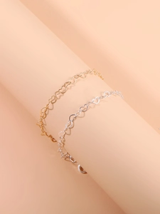 Detail of hollow heart link bracelets in gold and silver finish on display stand