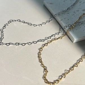 Detailed view of hollow heart-shaped chain bracelets in polished gold and silver finishes