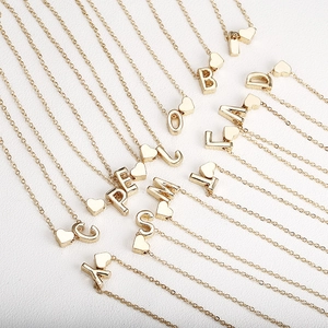 Elegant gold initial letter necklace with a small heart charm on a minimalist thin chain