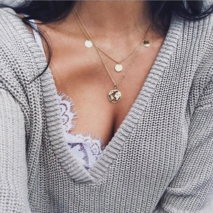 Layered gold necklace featuring delicate sequins and a hollow world map pendant on model
