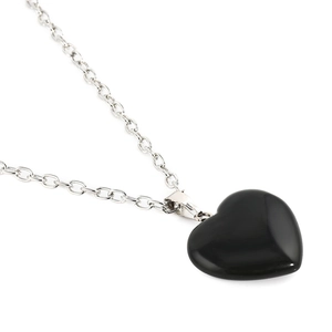Pendentif cœur en pierre noire polie avec chaîne à maillons argentés sur fond blanc