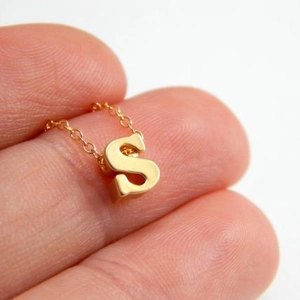 Minimalistische Goldkette mit S-Buchstabenanhänger poliert an den Fingern gehalten