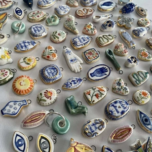 Macro view of assorted ceramic charms with hand-painted patterns and gold-plated edges