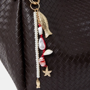 Detail of beaded bag charm with starfish, fish motifs and pearls on woven leather