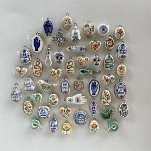 Detail showing various hand-painted ceramic charms with gold plating and metal loops
