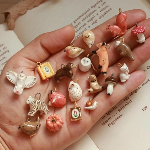 Miniature animal and nature charms set in 18K gold plated stainless steel shown on a hand