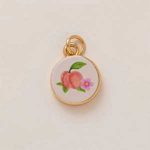 Détail macro du pendentif pêche et fleur plaqué or 18K avec finition peinte à la main
