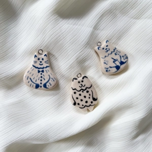 Detailed view of hand-painted ceramic cat pendants with blue and black patterns