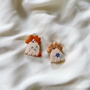 Hand-painted ceramic dog pendants with floral patterns on a white textured background