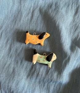 Detailed close-up of handmade ceramic dog pendants with floral and heart patterns