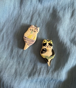 Detail of two hand-painted ceramic cat pendants in colorful bikinis for necklaces