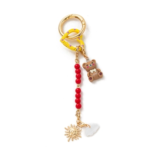 Detailed view of DIY keychain with brown bear toy and colorful decorative charms