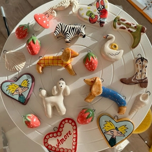 Artistic ceramic pendant collection with swan, dog, and strawberry shapes on a white tray